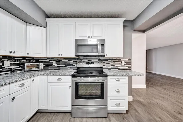 a kitchen with granite countertop white cabinets and white appliances