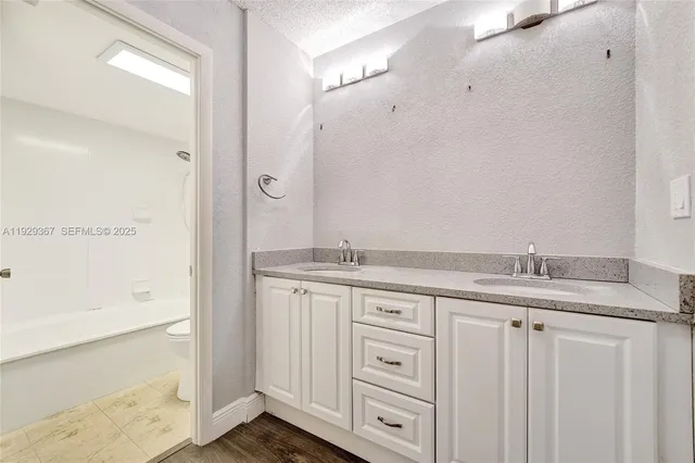 a view of a hallway with wooden floor and a bathroom