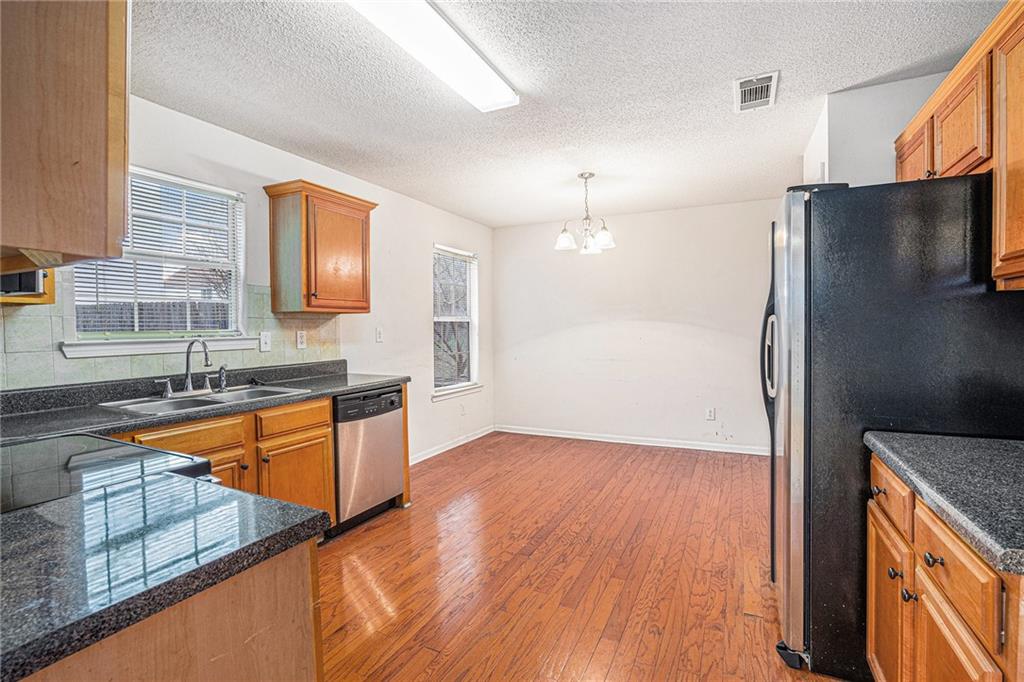 1915 Cornerstone Pass Way Conyers, GA 30012 - Photo 6 of 25 a kitchen with stainless steel appliances granite countertop a refrigerator a sink dishwasher and a stove with wooden floor
