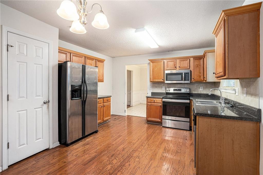 1915 Cornerstone Pass Way Conyers, GA 30012 - Photo 8 of 25 a kitchen with stainless steel appliances granite countertop a refrigerator a stove and a wooden floors