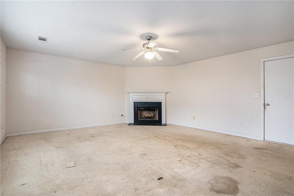 1915 Cornerstone Pass Way Conyers, GA 30012 - Photo 10 of 25 an empty room with a ceiling fan and a fireplace