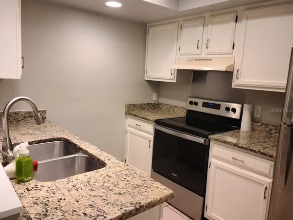 a kitchen with white cabinets a sink and dishwasher