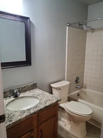 a bathroom with a granite countertop toilet sink and mirror