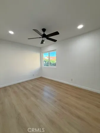 an empty room with wooden floor and a ceiling fan