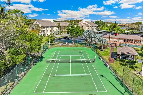 a view of a tennis ground with large trees