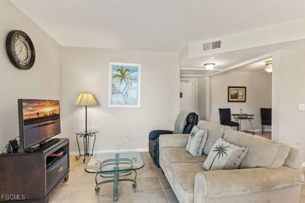 a living room with furniture a flat screen tv and a window