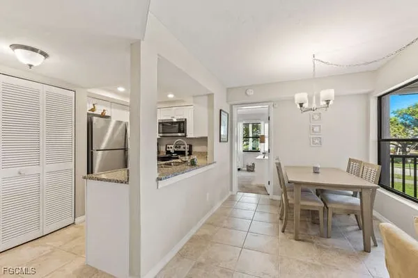 a kitchen with stainless steel appliances kitchen island granite countertop a refrigerator a stove a dining table and chairs with wooden floor