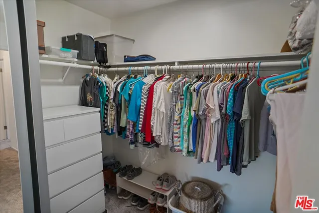 a view of walk in closet with clothes and shoes