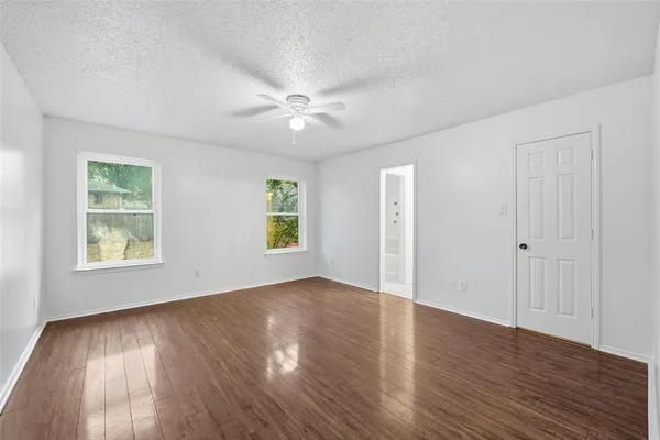 an empty room with wooden floor and windows