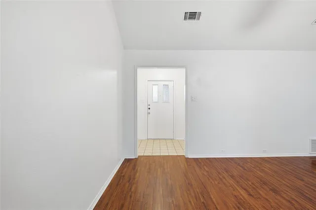 a view of an empty room with wooden floor and closet