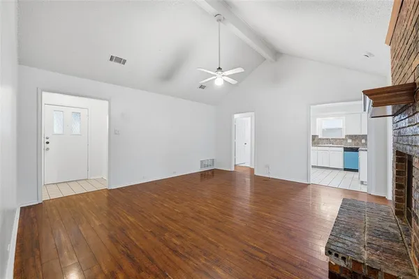 an empty room with wooden floor fireplace and windows