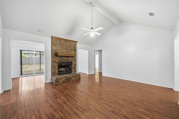 an empty room with wooden floor fireplace and windows