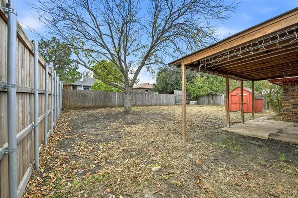 a backyard of a house with large trees and wooden fence