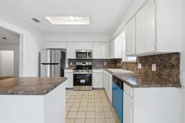 a kitchen with stainless steel appliances granite countertop a refrigerator a stove top oven a sink and dishwasher