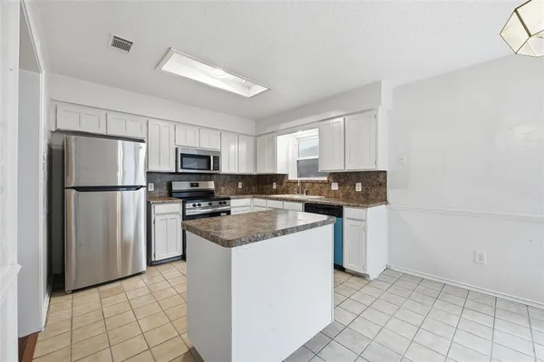 a kitchen with stainless steel appliances granite countertop a refrigerator a stove a sink and a microwave