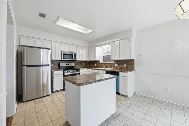 a kitchen with stainless steel appliances granite countertop a refrigerator a stove a sink and a microwave