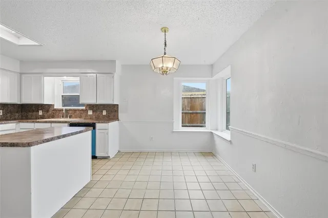 a kitchen with granite countertop white cabinets and window