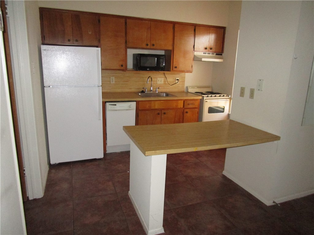 621 West 37th Street, Unit 105 Austin, TX 78705 - Photo 4 of 9 a kitchen with a refrigerator a microwave a sink and cabinets