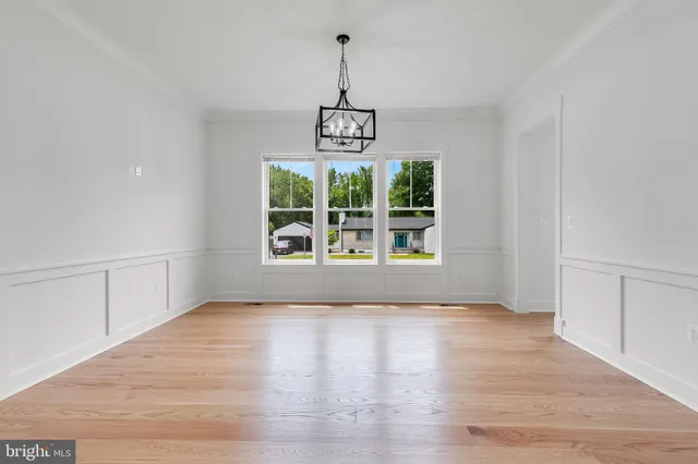 a view of an empty room with wooden floor and windows