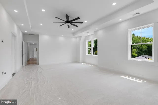 an empty room with windows and ceiling fan
