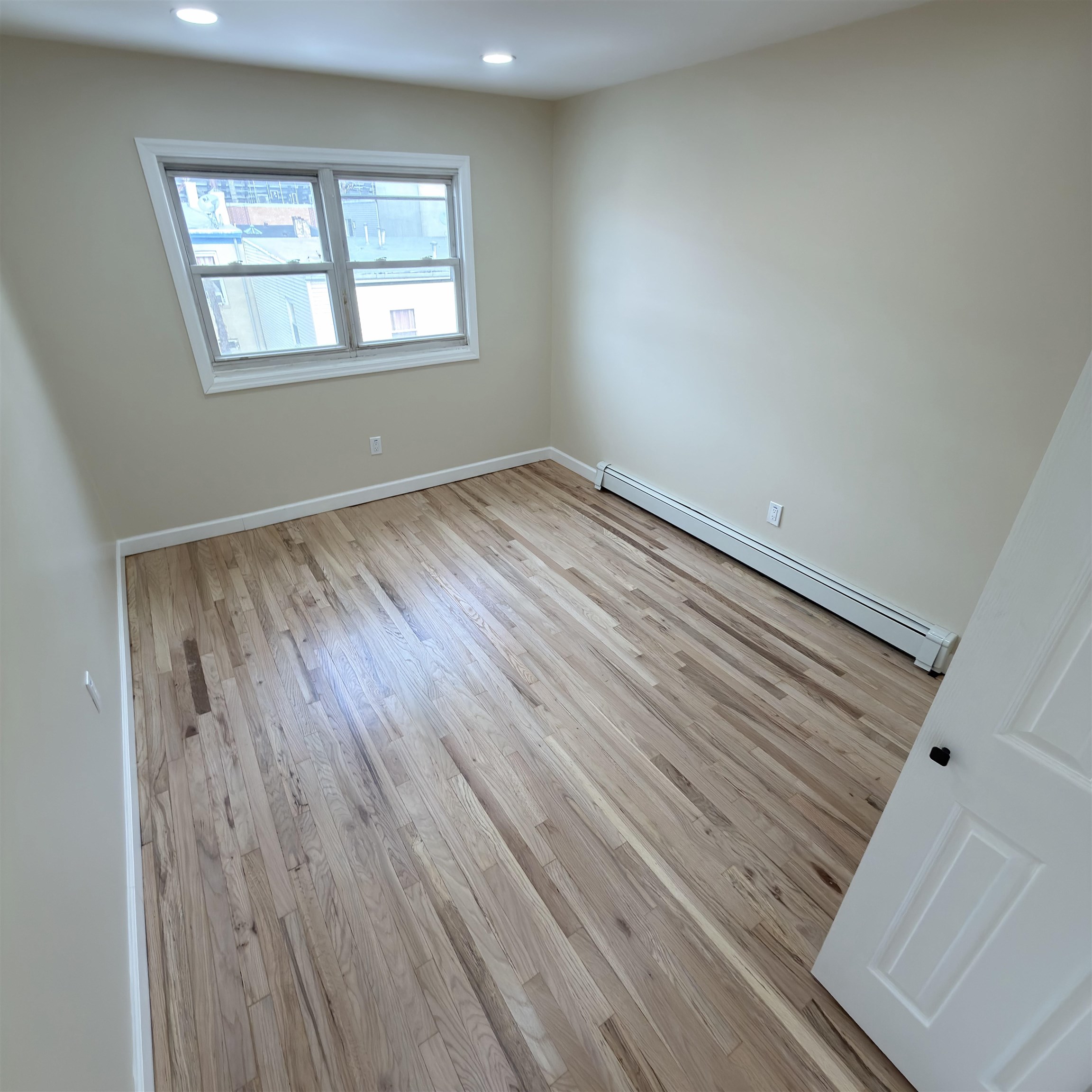 810 23rd Street, Unit 3 Union City, NJ 07087 - Photo 4 of 12 an empty room with wooden floor and windows