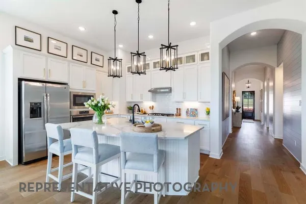 a kitchen with stainless steel appliances kitchen island granite countertop a dining table chairs and white cabinets