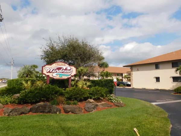 a view of a sign board with a big yard and large trees