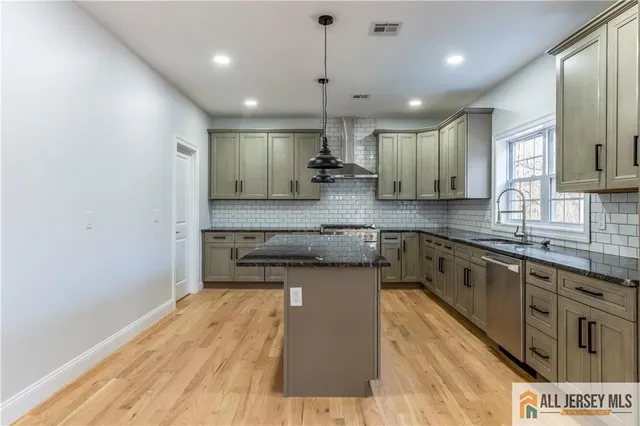 a large kitchen with stainless steel appliances granite countertop a stove a sink a refrigerator and a granite counter tops with wooden floors