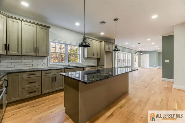a large kitchen with stainless steel appliances granite countertop a stove and a wooden floors