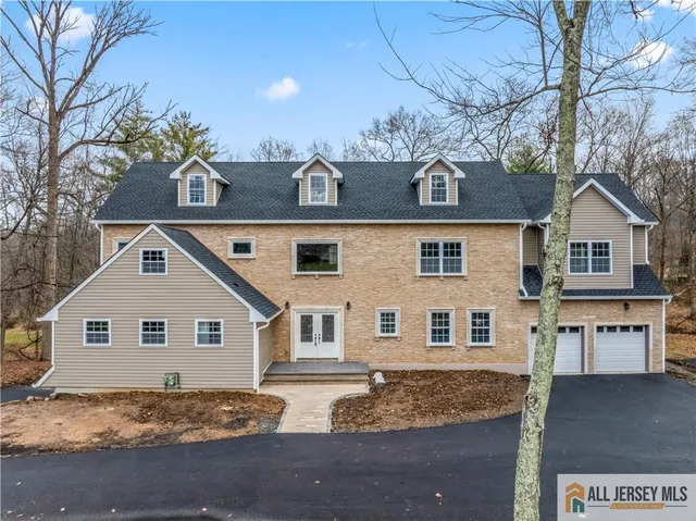 a view of a white house next to a yard with large tree
