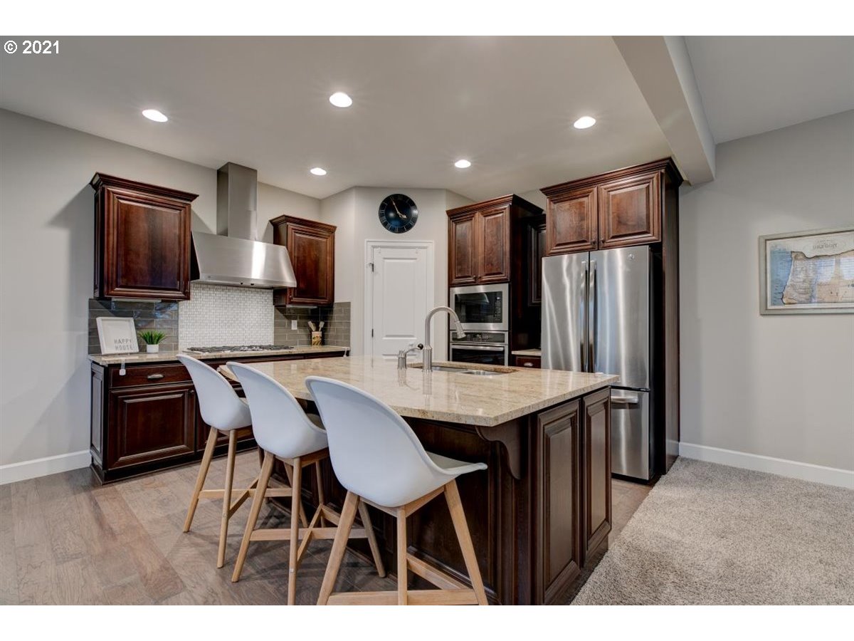 17468 Northwest Woodrush Way Portland, OR 97229 - Photo 10 of 32 a kitchen with stainless steel appliances kitchen island granite countertop a table chairs microwave and sink