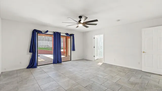 a view of an empty room with a ceiling fan and window