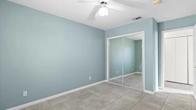 an empty room with closet and a chandelier fan