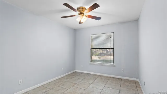 an empty room with windows and fan