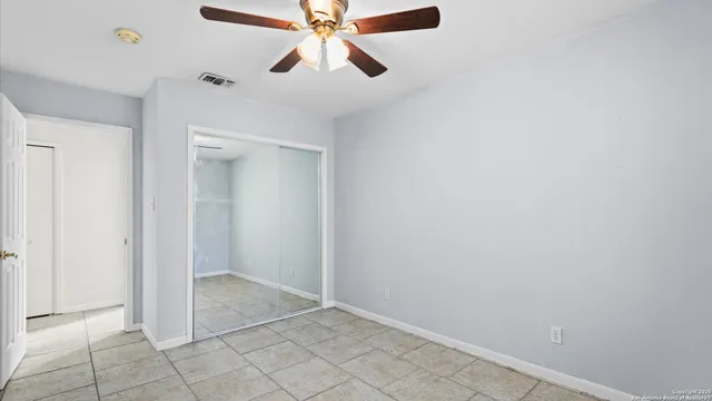 an empty room with closet and a chandelier fan
