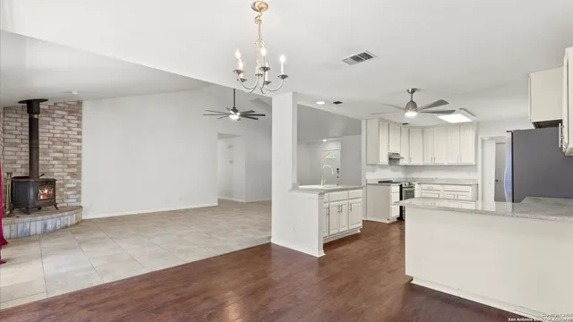 a large kitchen with a refrigerator a stove a sink dishwasher a dining table and chairs with wooden floor