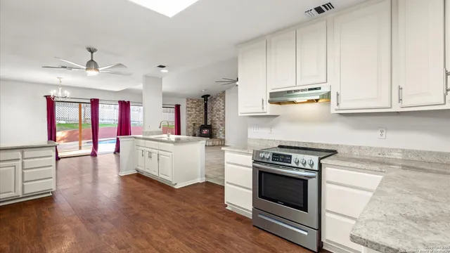 a kitchen with stainless steel appliances granite countertop a stove and white cabinets