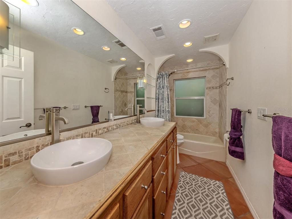 2602 Firetree Lane Venice, FL 34292 - Photo 15 of 31 a bathroom with a double vanity sink a mirror and a bathtub