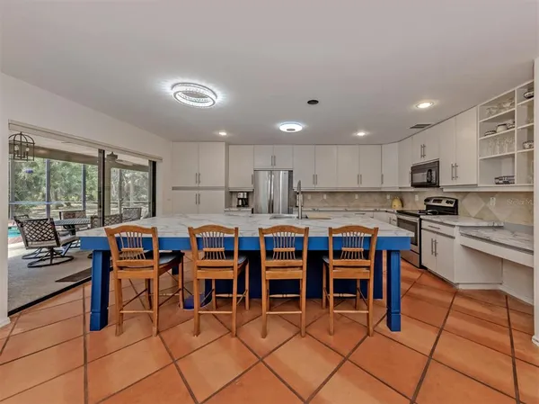 a open kitchen with granite countertop a stove a sink a dining table and chairs