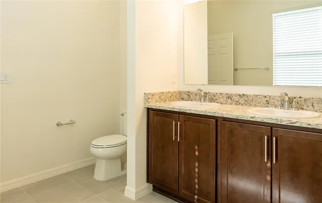a bathroom with a granite countertop sink and a toilet