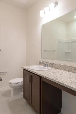 a bathroom with a granite countertop sink a toilet and a mirror