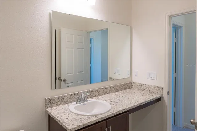 a bathroom with a granite countertop sink and a mirror