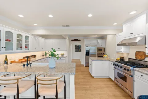 a kitchen with stainless steel appliances kitchen island granite countertop a stove a sink a dining table and chairs