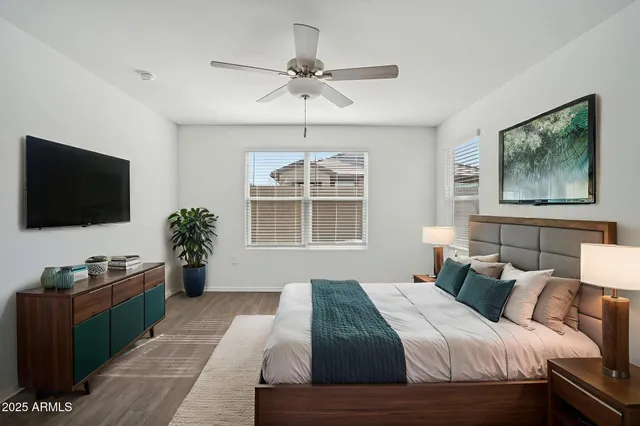 an empty room with wooden floor ceiling fan and windows