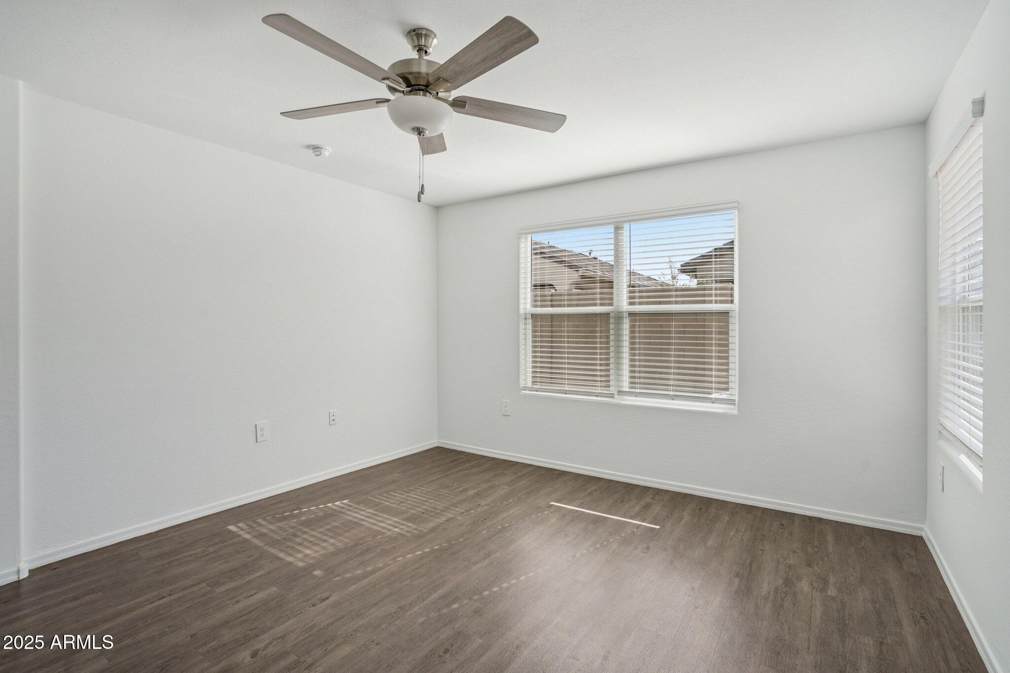 1566 East Yeoman Drive Casa Grande, AZ 85122 - Photo 18 of 28 an empty room with wooden floor ceiling fan and windows