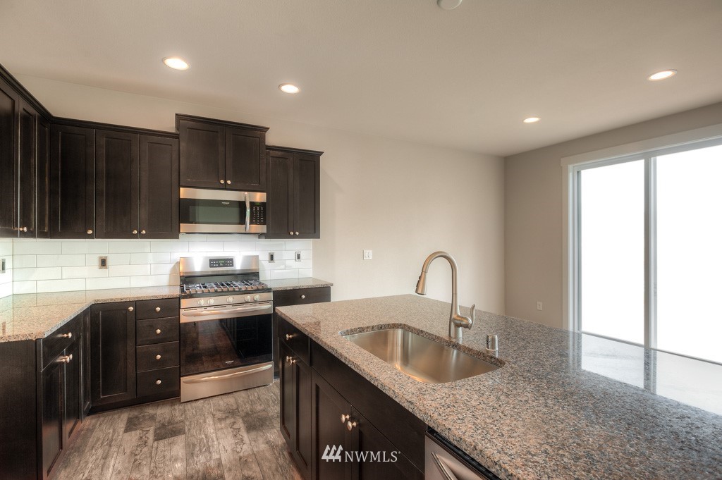 21118 Meridian Drive Southeast, Unit P4 Bothell, WA 98021 - Photo 10 of 29 a kitchen with granite countertop a sink and a stove top oven