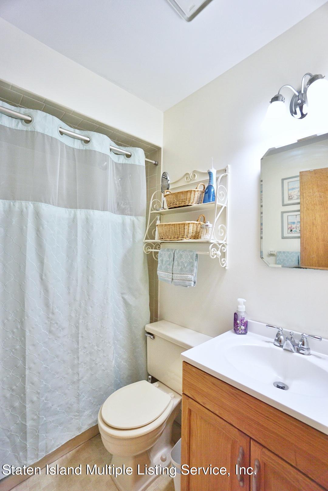 563 Mill Road Staten Island, NY 10306 - Photo 13 of 32 a bathroom with a sink a toilet and a shower curtain