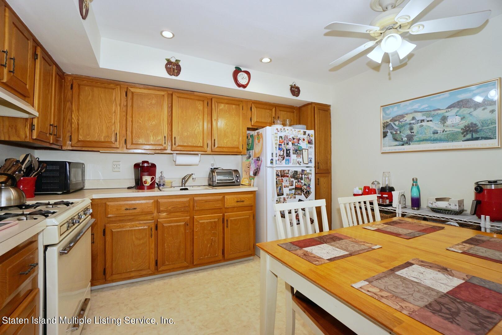 563 Mill Road Staten Island, NY 10306 - Photo 17 of 32 a kitchen with stainless steel appliances granite countertop a sink dishwasher stove and refrigerator with wooden cabinets