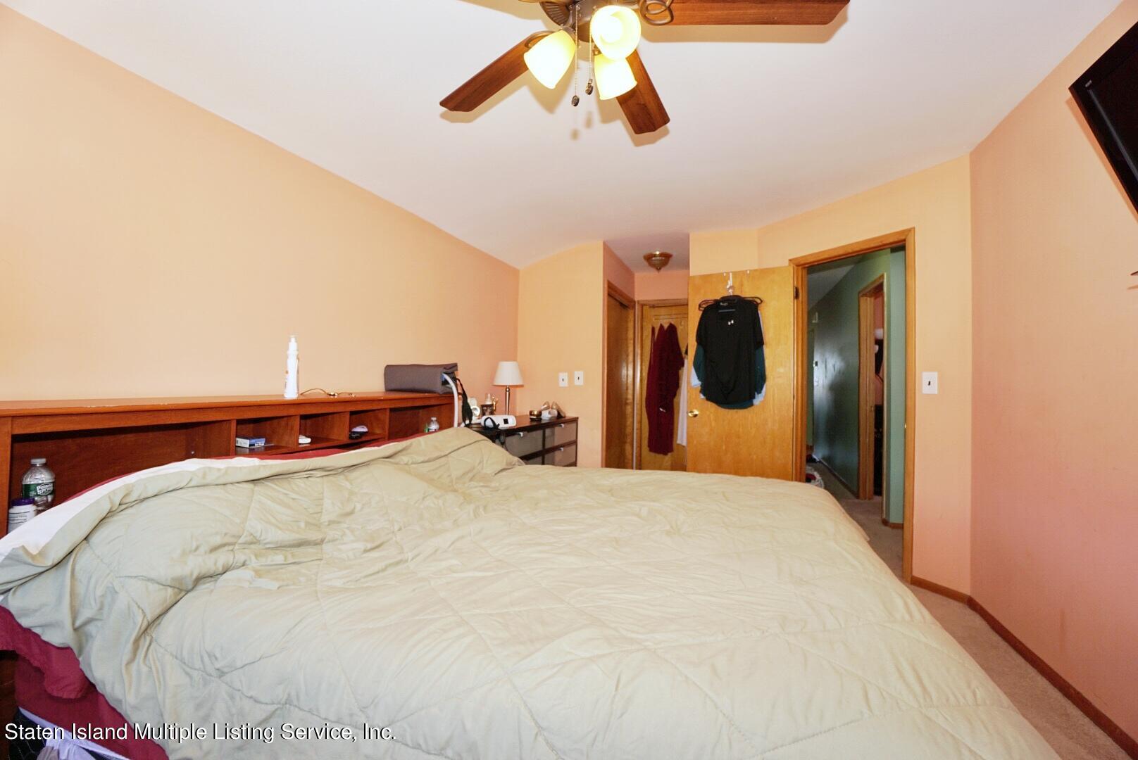 563 Mill Road Staten Island, NY 10306 - Photo 9 of 32 a bed room with a bed and a chandelier
