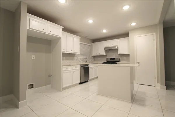 a kitchen with kitchen island granite countertop a stove a sink and a refrigerator